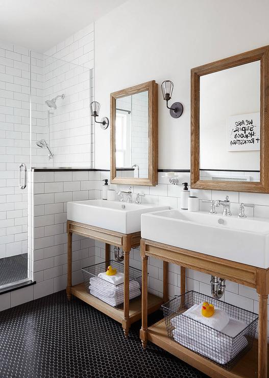 fun shared kids bath with two wood vanities, large white subway walls, black hex floors