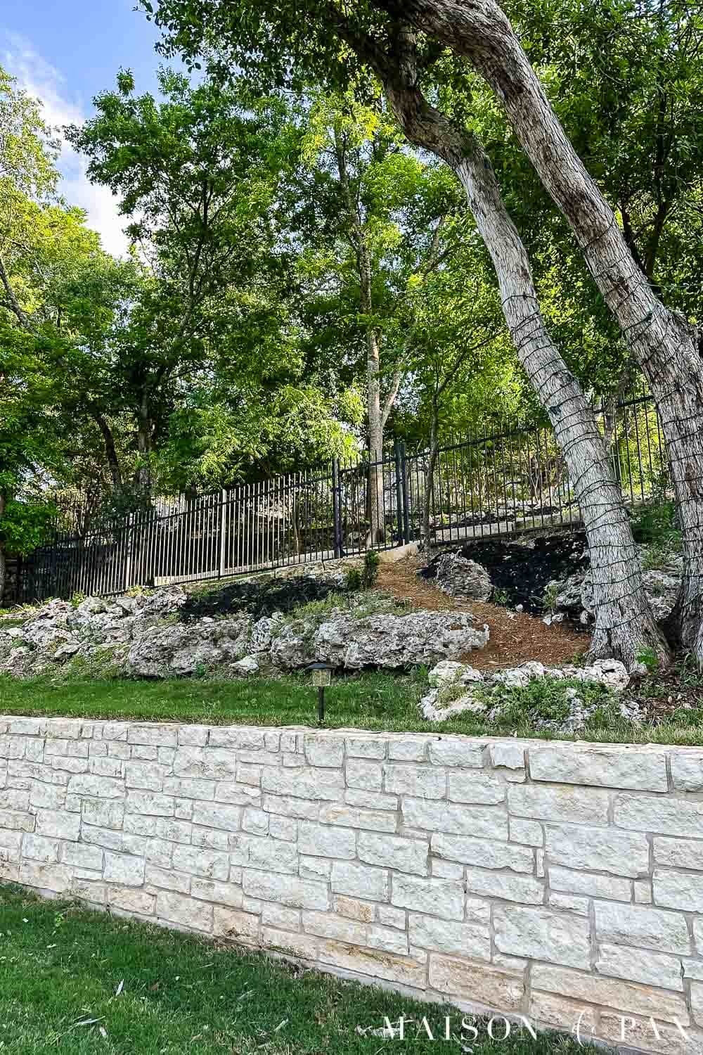 limestone wall, crushed granite pathways, and black mulch beds