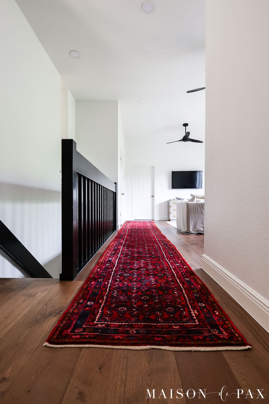 game room beside stairs with brown oak floors and sw pure white walls