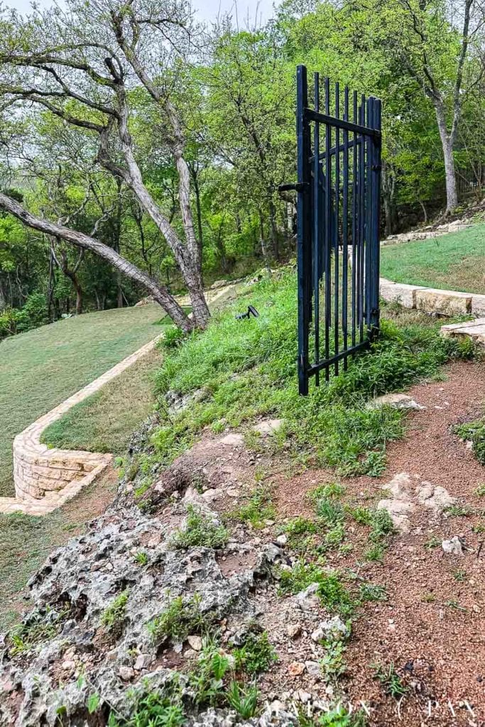 iron fence and decomposed granite pathway overgrown