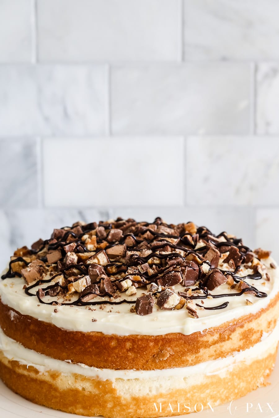 White naked cake with chopped candy on top! Learn how to make and decorate a naked cake. #nakedcake #nakedcakerecipe #cakefrosting #howtofrost #cakerecipe #creamcheesefrosting #cakedecorating #whitecake