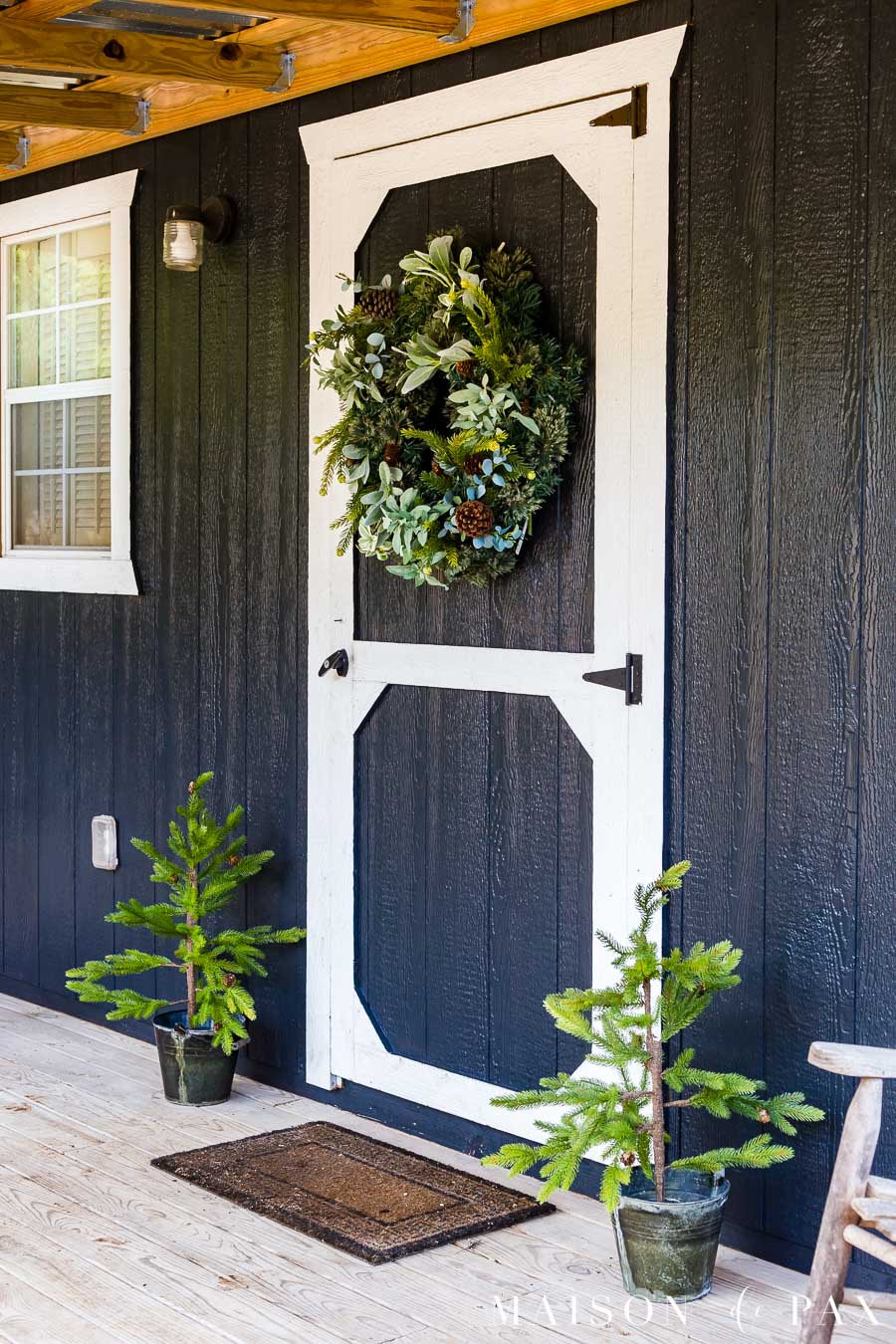 two tiny Christmas trees in rustic buckets on either side of the front door