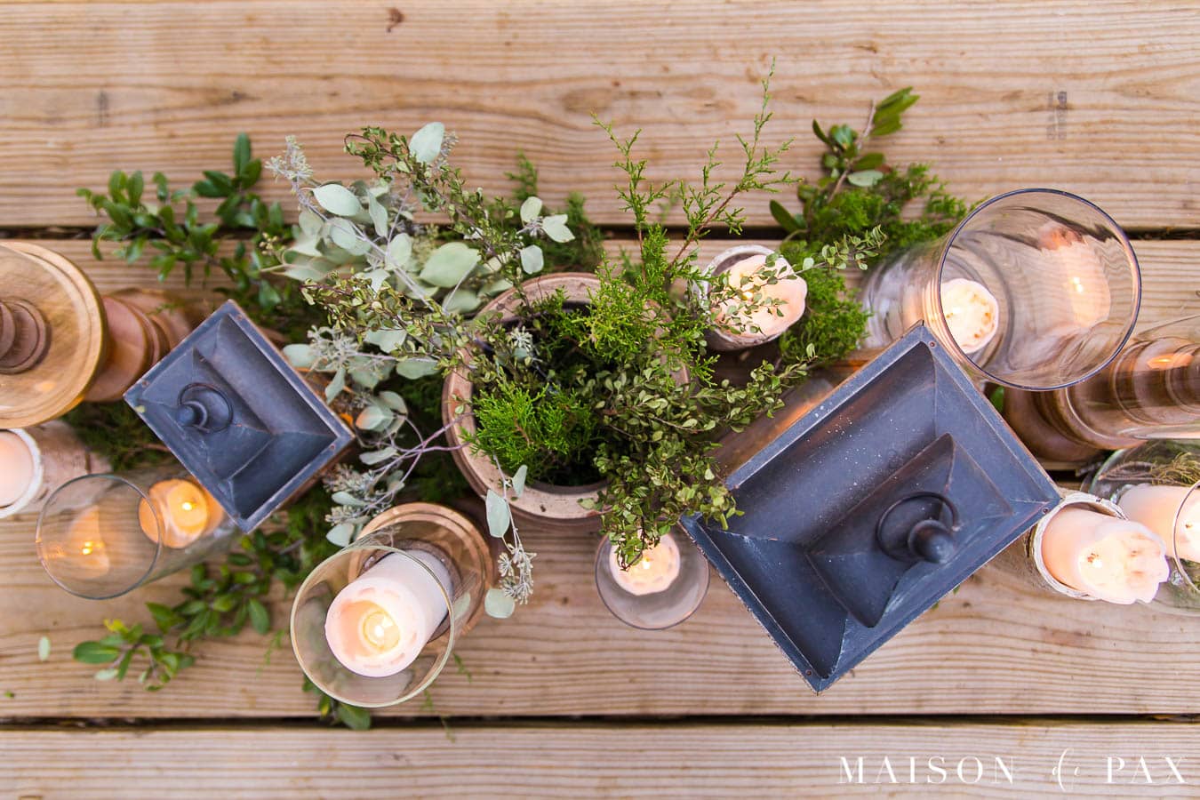 rustic dining table with centerpiece of wooden candlesticks, lanterns, and glass vases | Maison de Pax