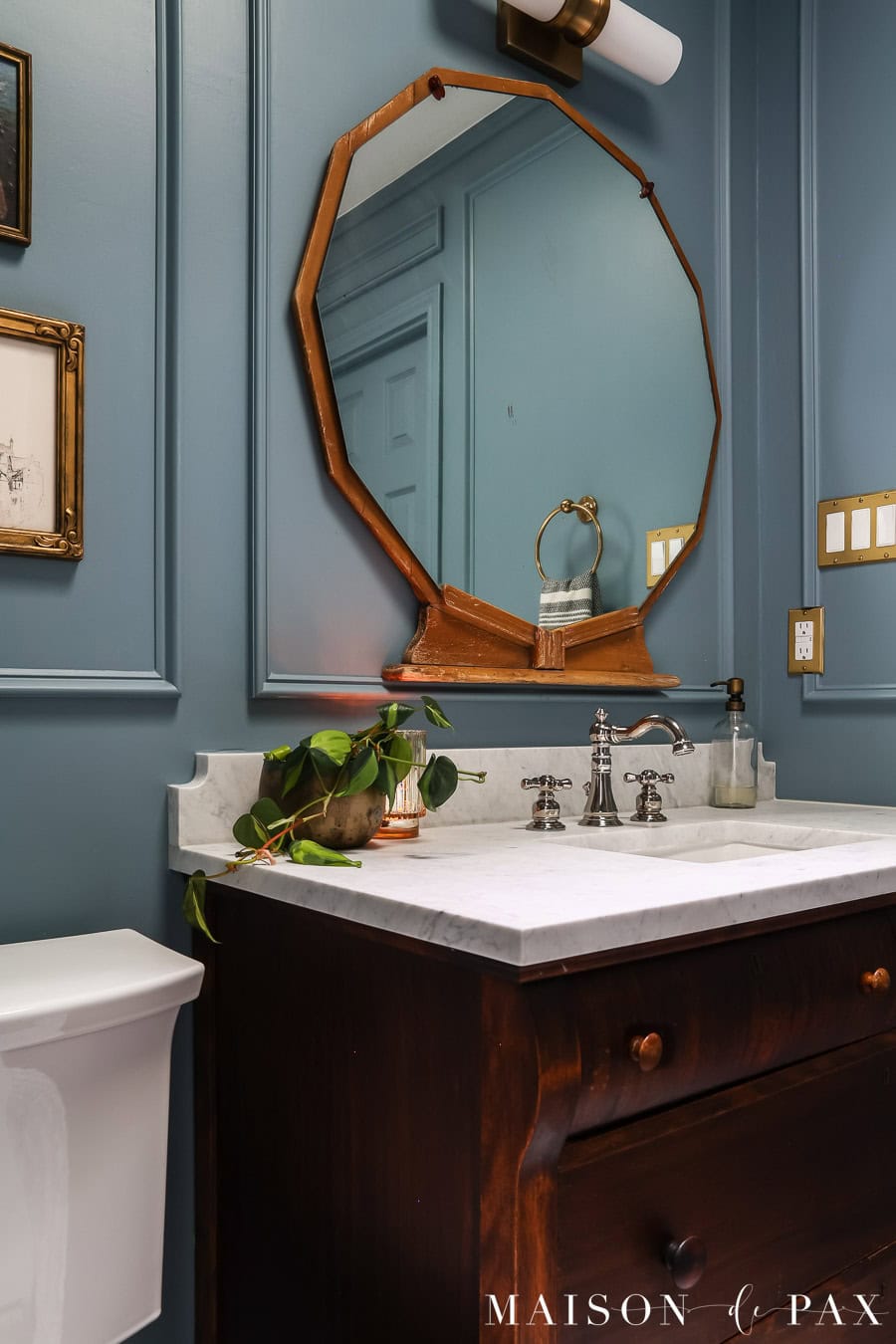 dark wood vanity with polished nickel faucet, gold lighting, and blue walls