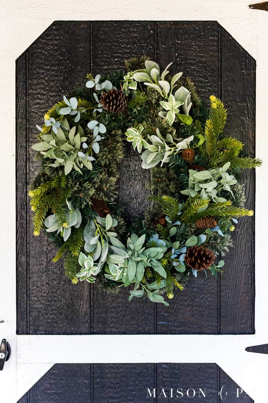 Full green wreath on a black barn door with white trim