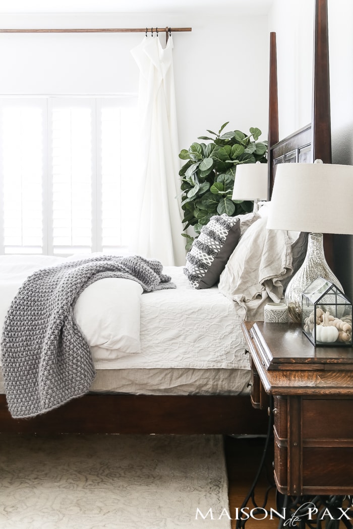 four poster wood bed is offset with white bedding and gray accents- Maison de Pax