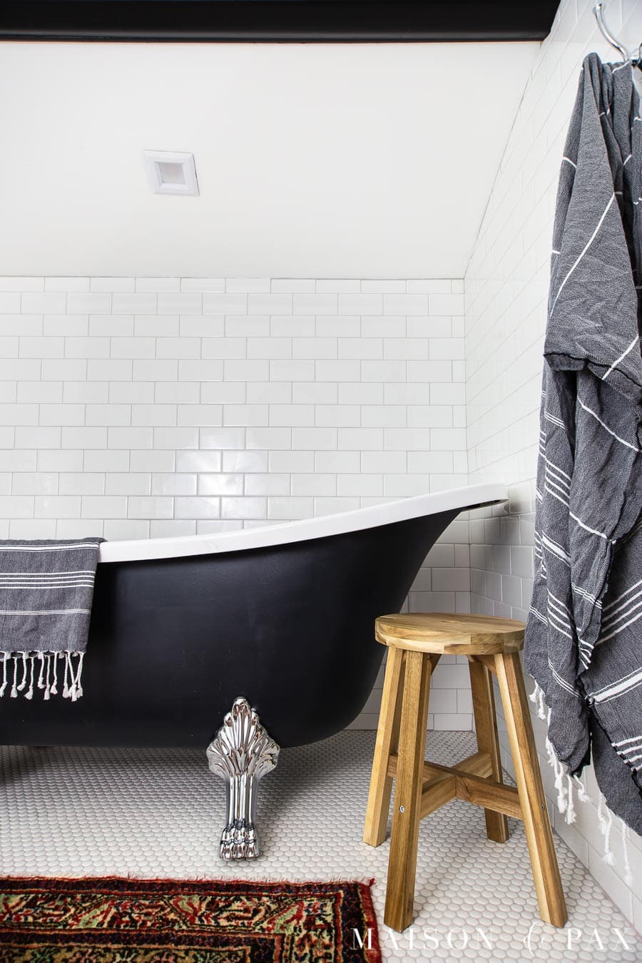 black clawfoot tub with chrome legs and a wooden stool | Maison de Pax