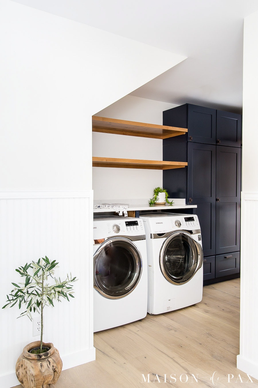 navy laundry room with wood shelves under stairs | Maison de Pax