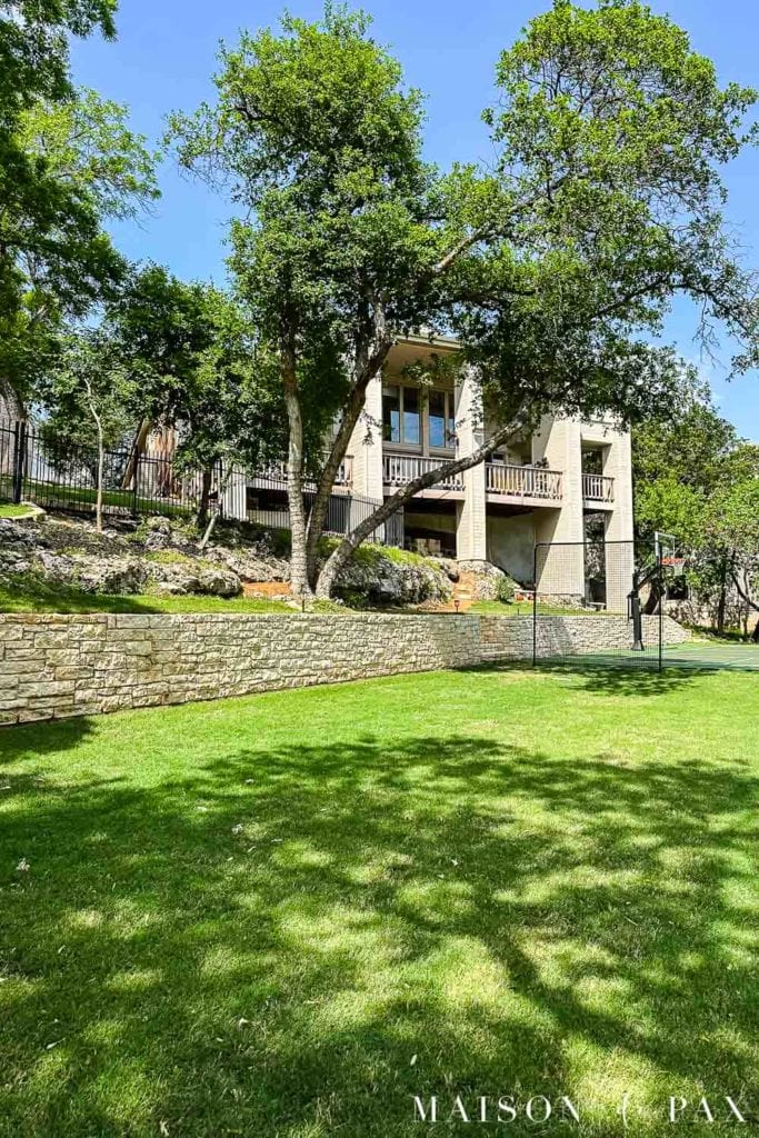 freshly pressure washed wall in big backyard with house built up on pillars