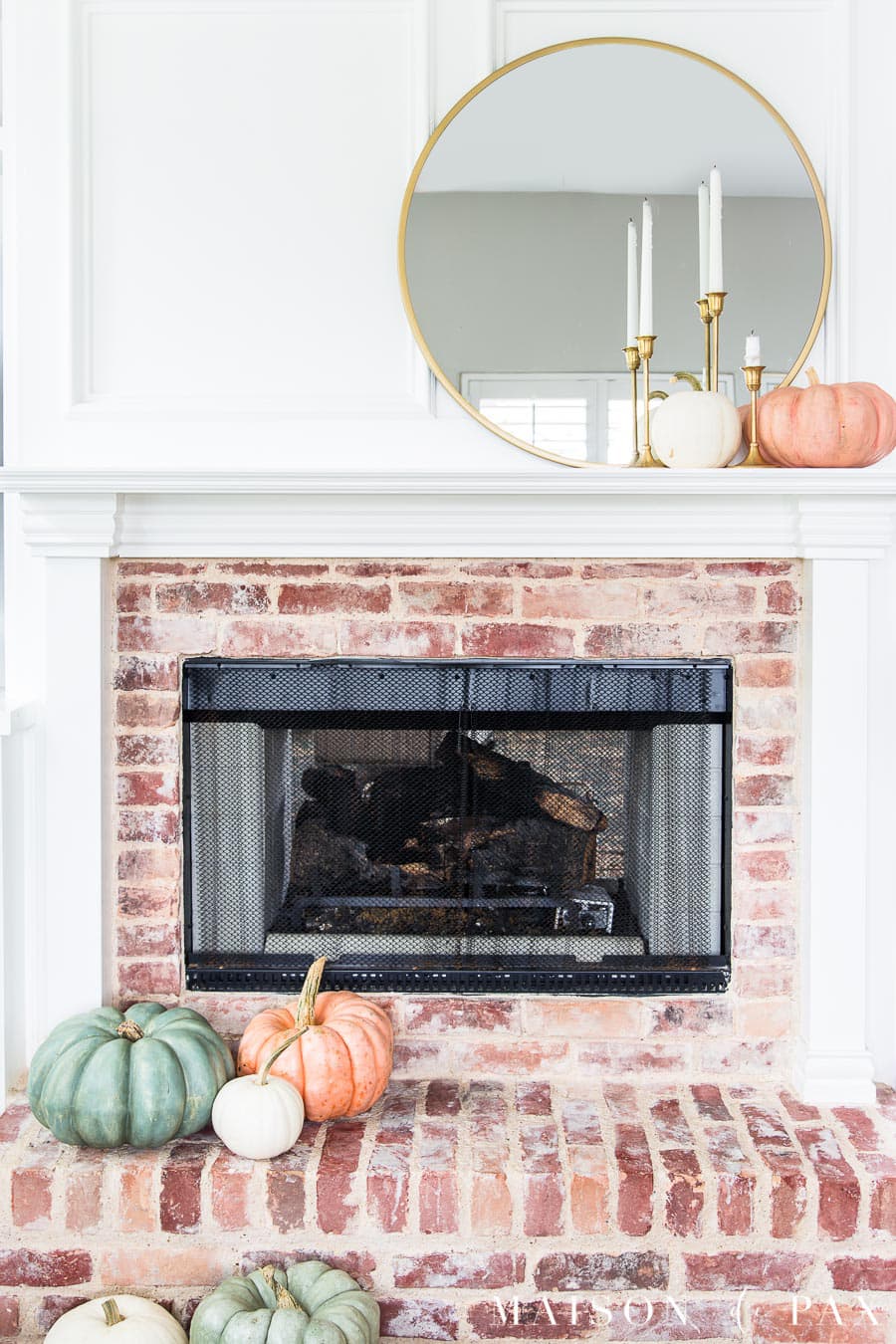white mantel with red brick fireplace decorated with green and pink heirloom pumpkins