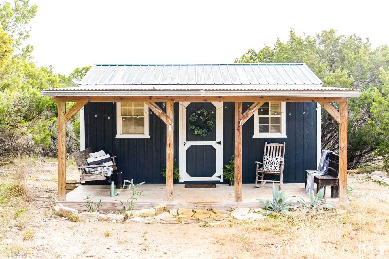 Black and white tiny house with deep front porch in the country