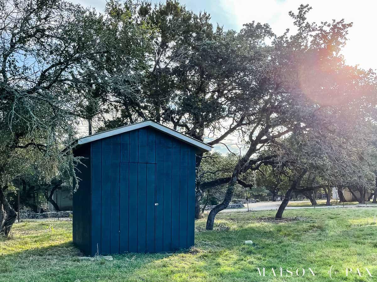 black shed out in field with oak trees and metal roof