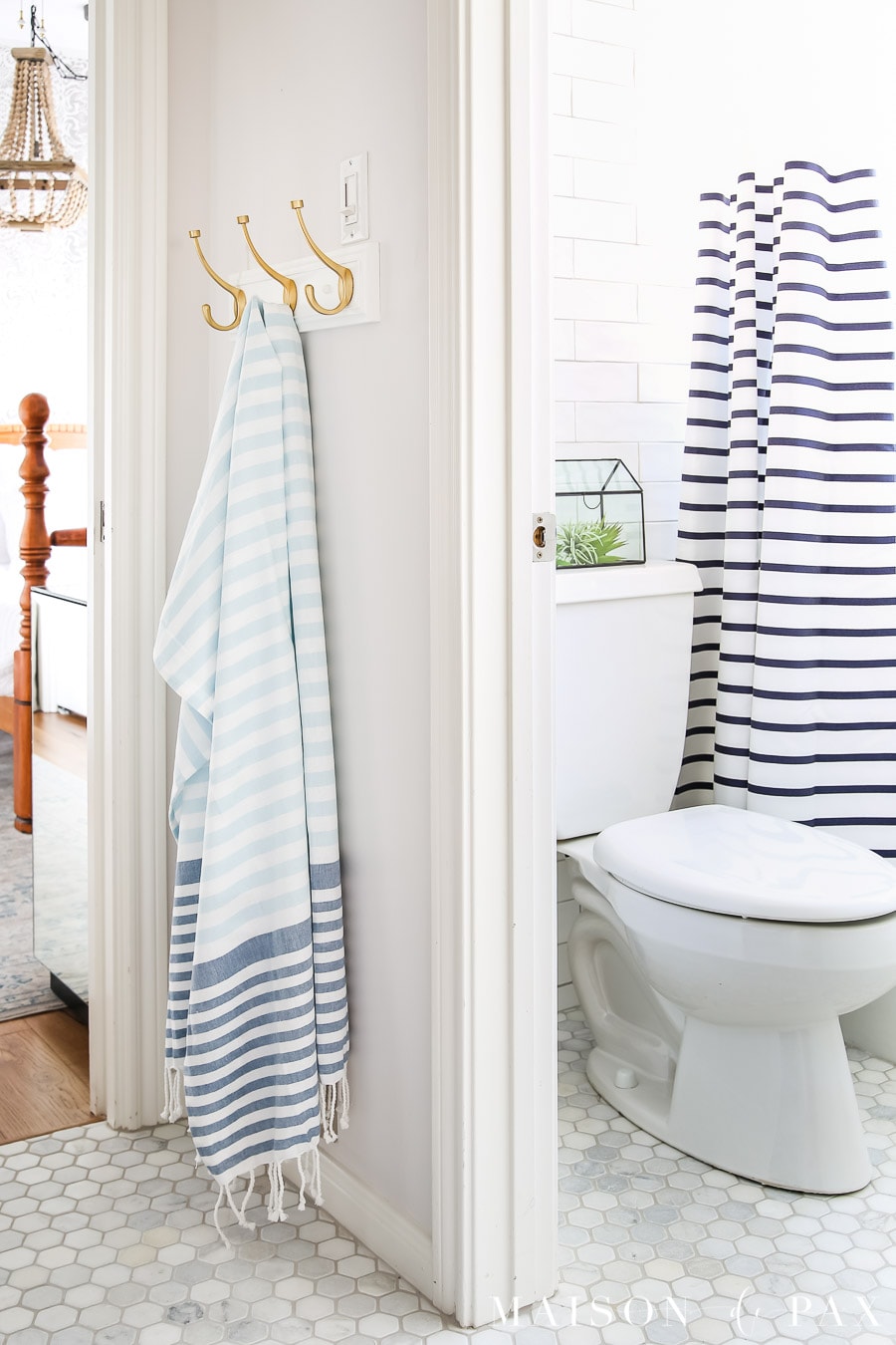 water closet with all tile white walls and tumbled hex marble floors