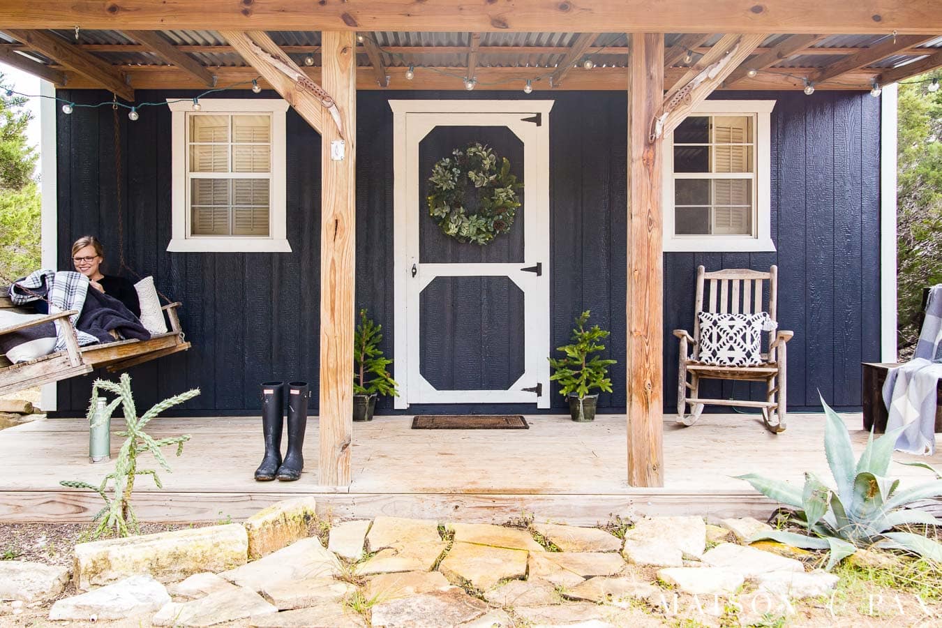 rustic front porch with cedar posts on a black tiny house with white trim