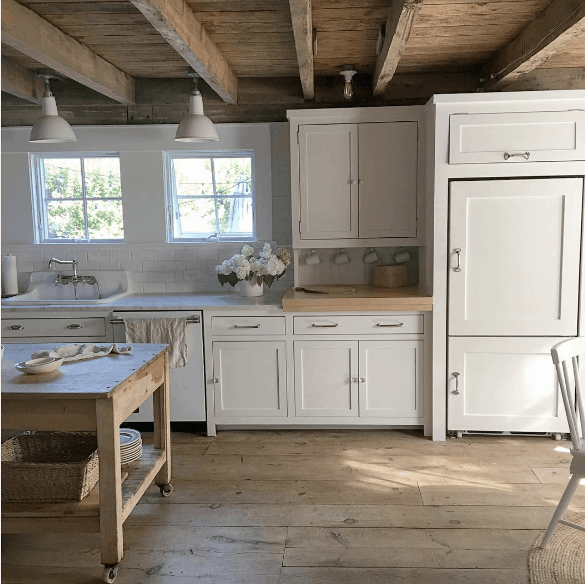 White Flower Farmhouse kitchen: rustic wood floors, white cabinets, marble counters, exposed ceiling beams- Maison de Pax