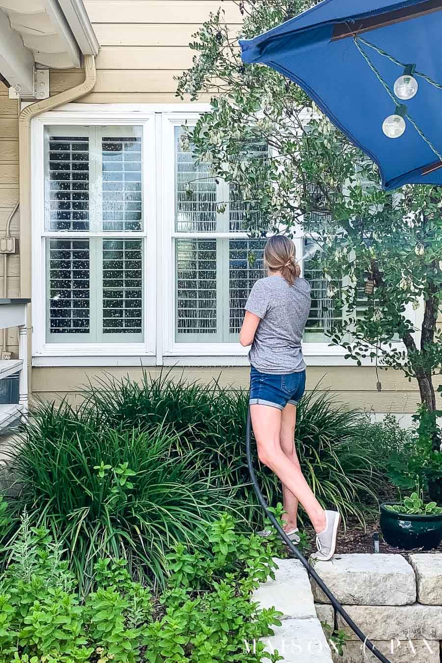 woman washing exterior windows with hose | Maison de Pax