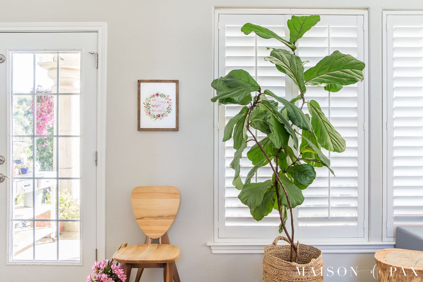 wooden chair with artwork beside glass door | Maison de Pax