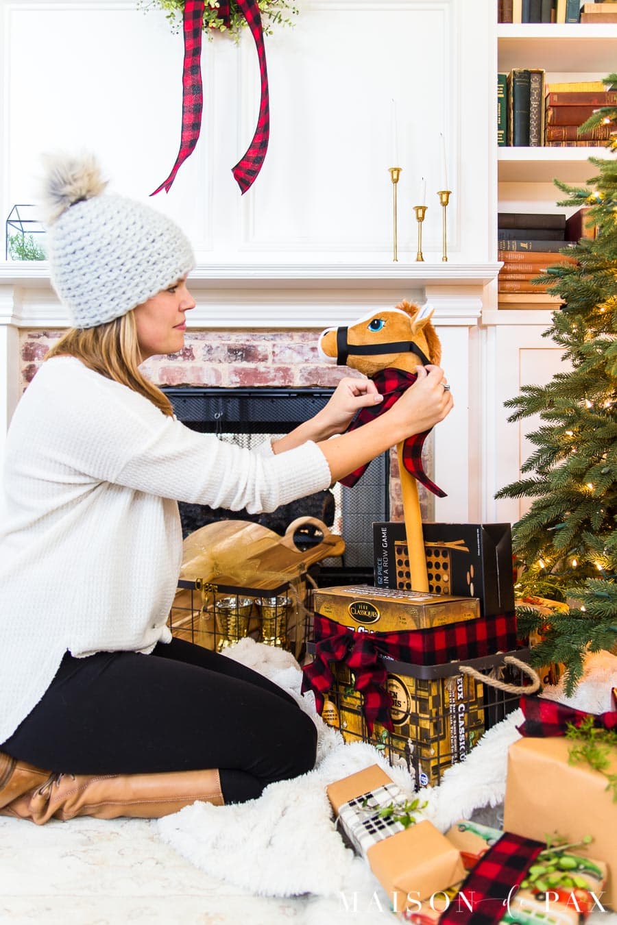 woman tying ribbon around stick horse beside Christmas tree | Maison de Pax