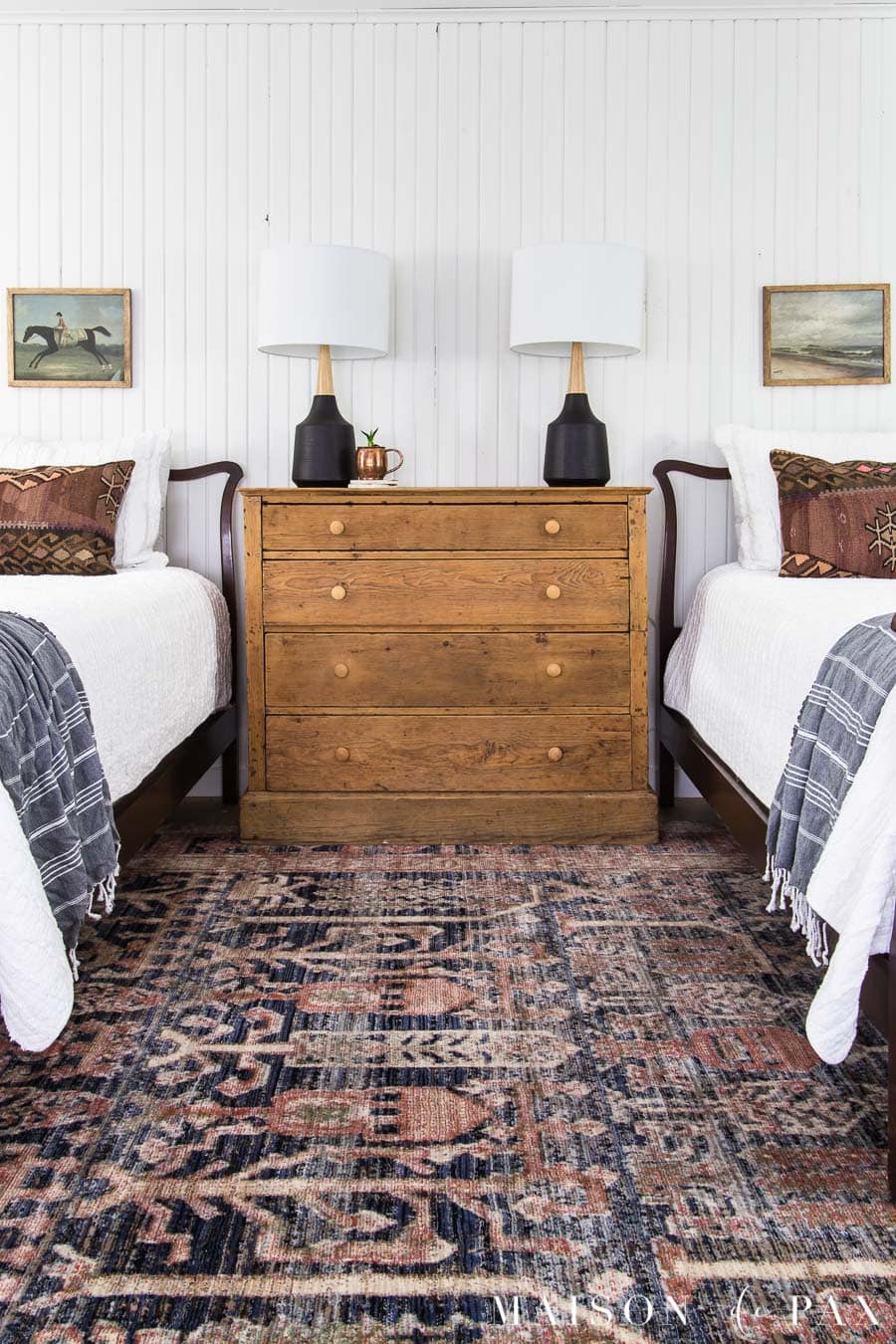 twin bedroom with white vertical shiplap walls and vintage art