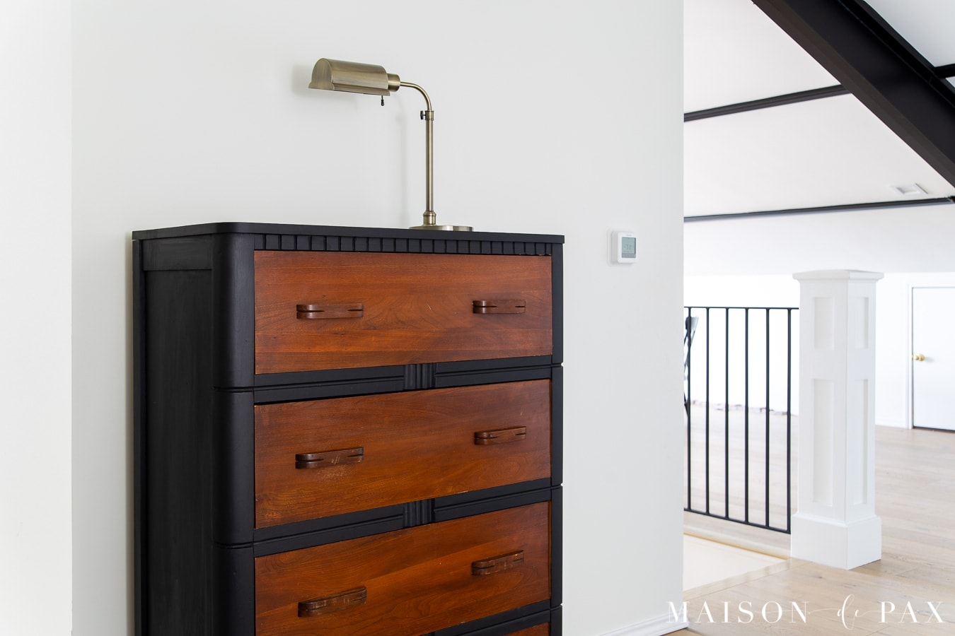 attic remodel: white room with black beams and black dresser with wood drawers