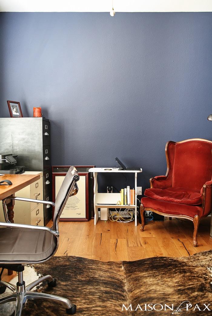 deep navy blue office with rustic wood floors, lots of bookcases, and an eclectic, collected vibe