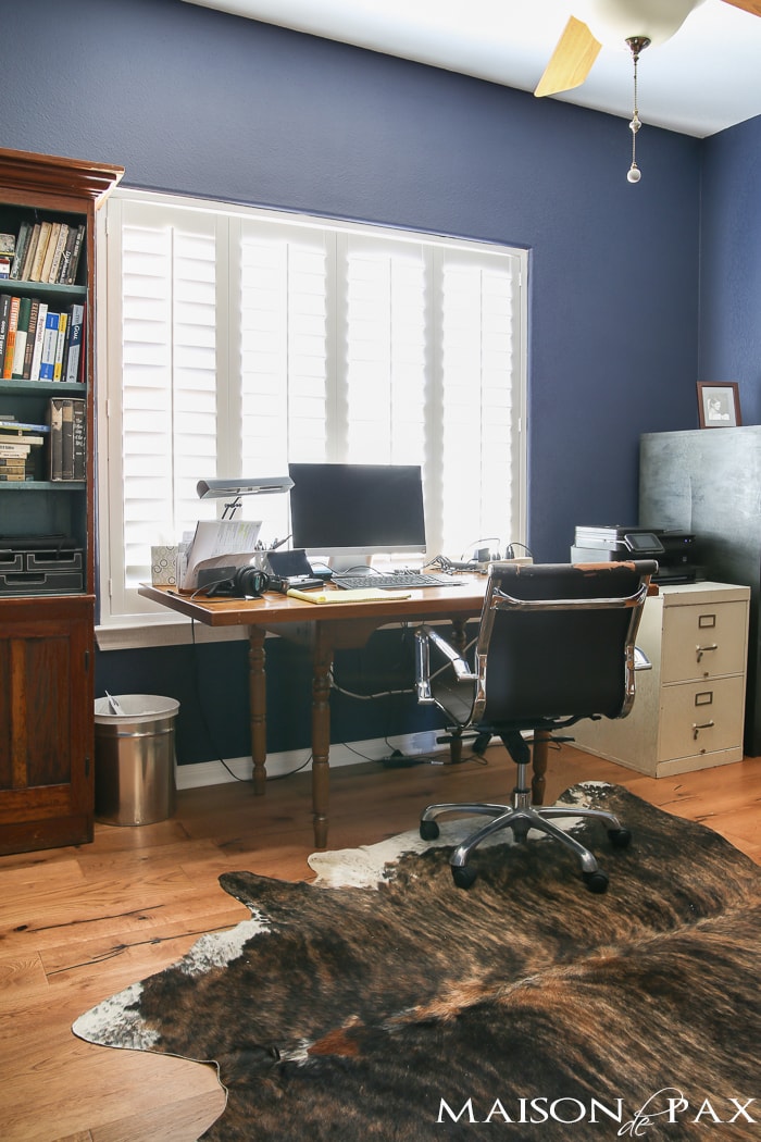 deep navy blue office with rustic wood floors, lots of bookcases, and an eclectic, collected vibe