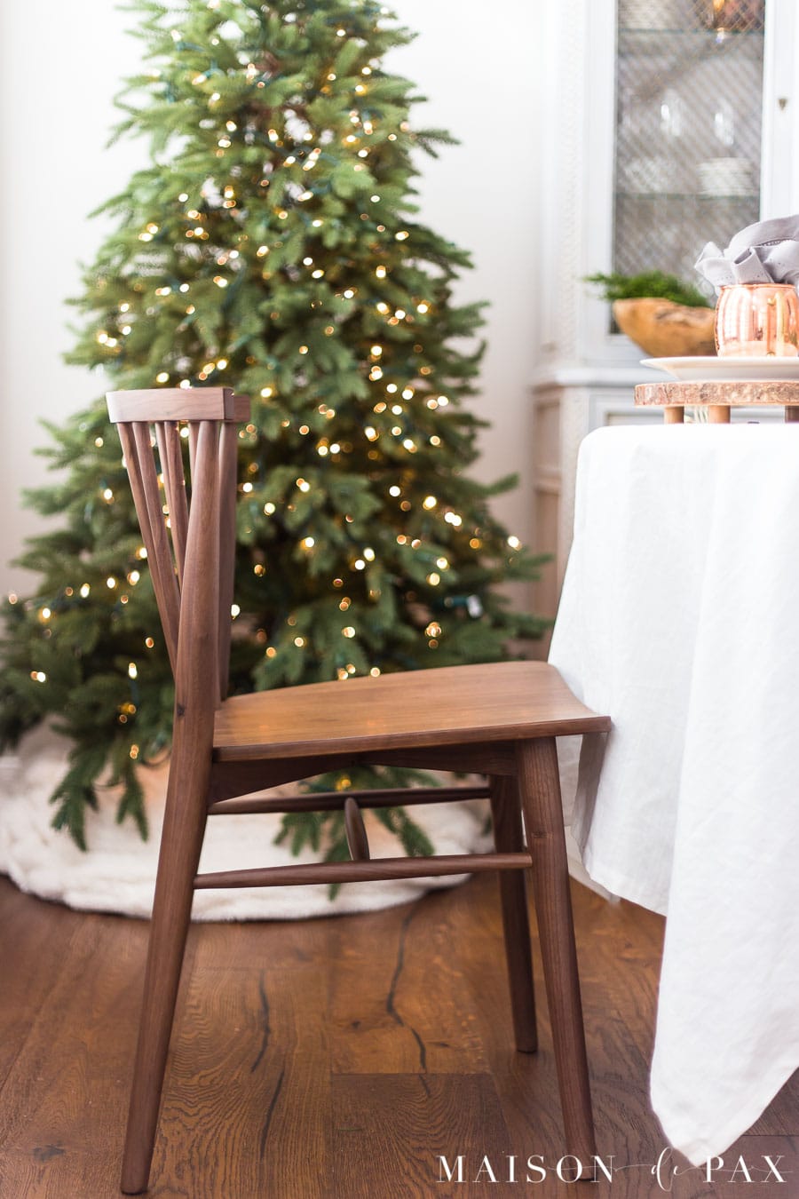 walnut modern farmhouse dining chair in front of green Christmas tree with lights