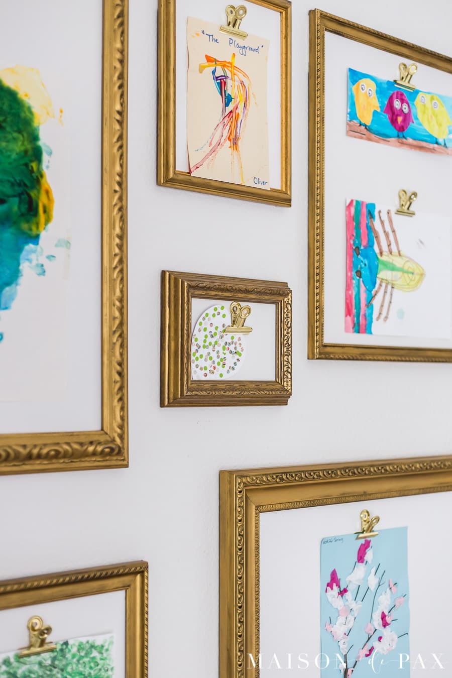 large gold clips hold children's artwork for display | Maison de Pax