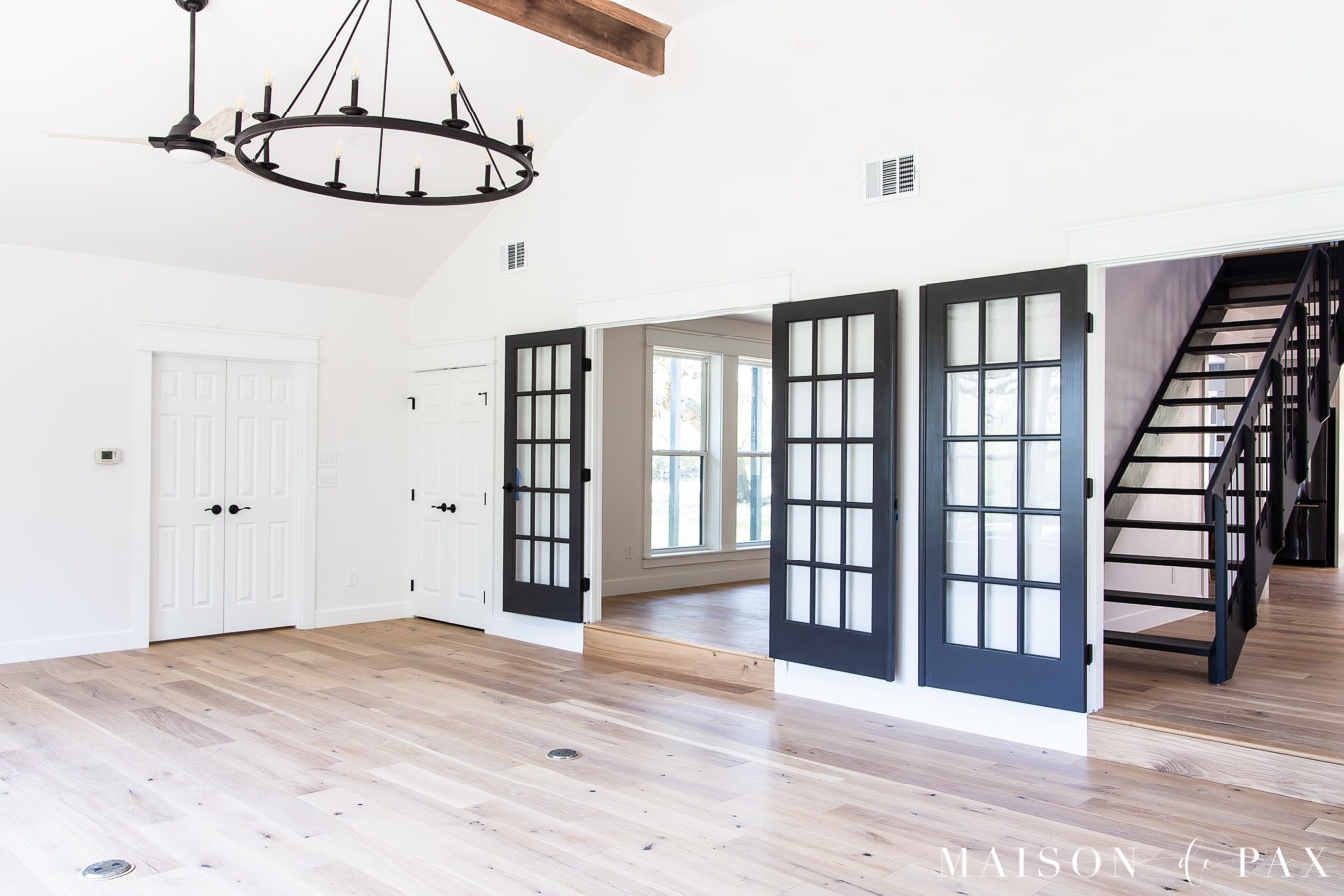 wide plank oak floors with ceiling beams and black fans