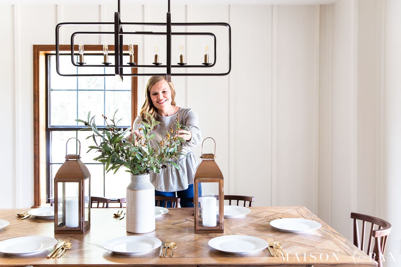 woman arranging olive branches on dining table | Maison de Pax