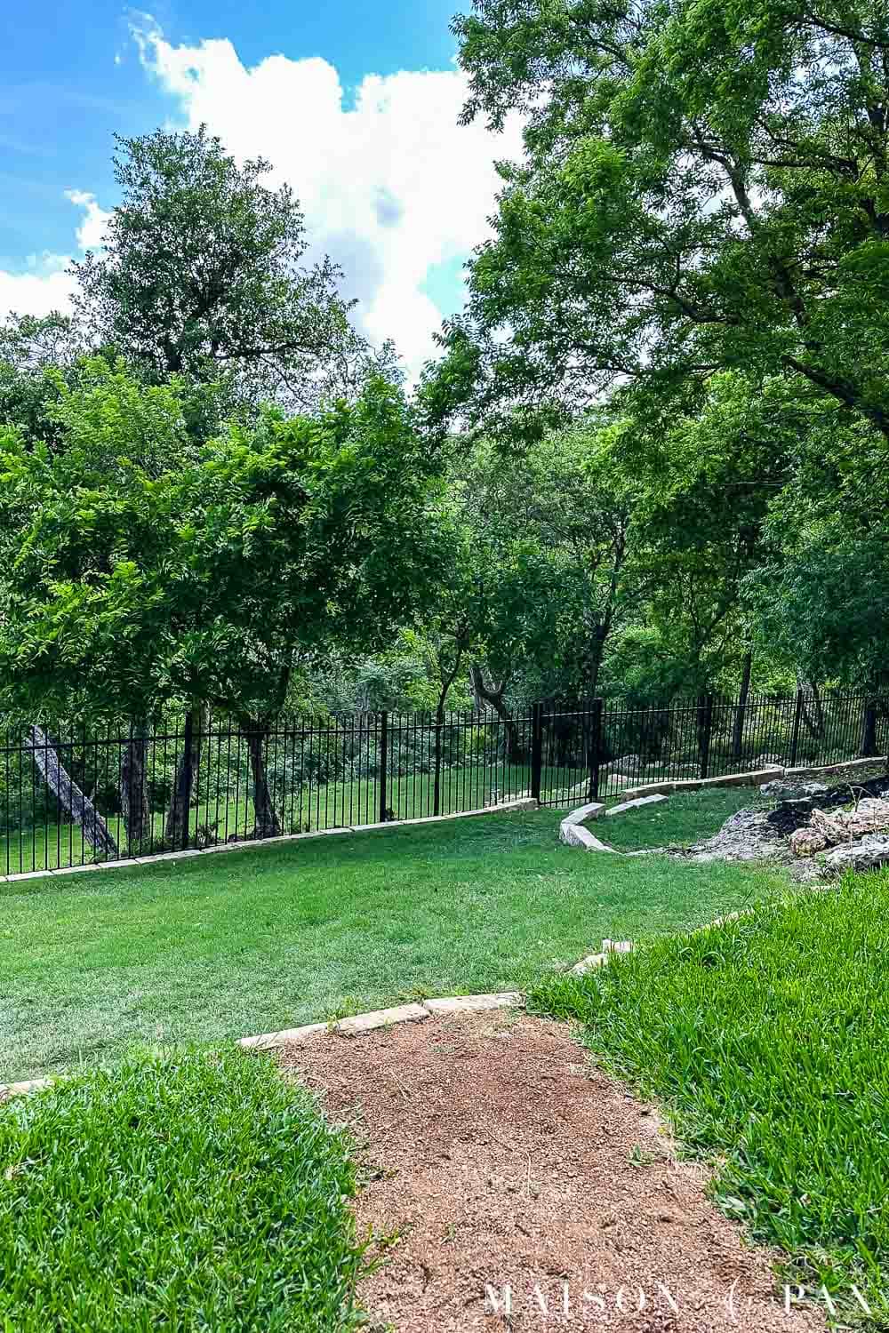 lush green lawn that slopes down to an iron fence