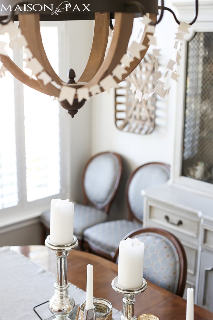 sewn white paper flags draped around a wine barrel chandelier for a festive look