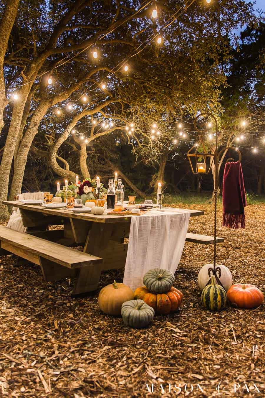 outdoor friendsgiving nighttime table with string lights | Maison de Pax