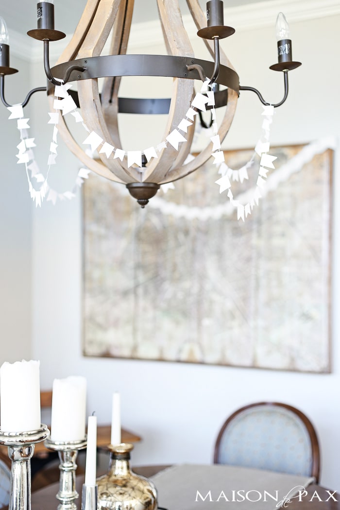 sewn white paper flags draped around a wine barrel chandelier for a festive look- Maison de Pax