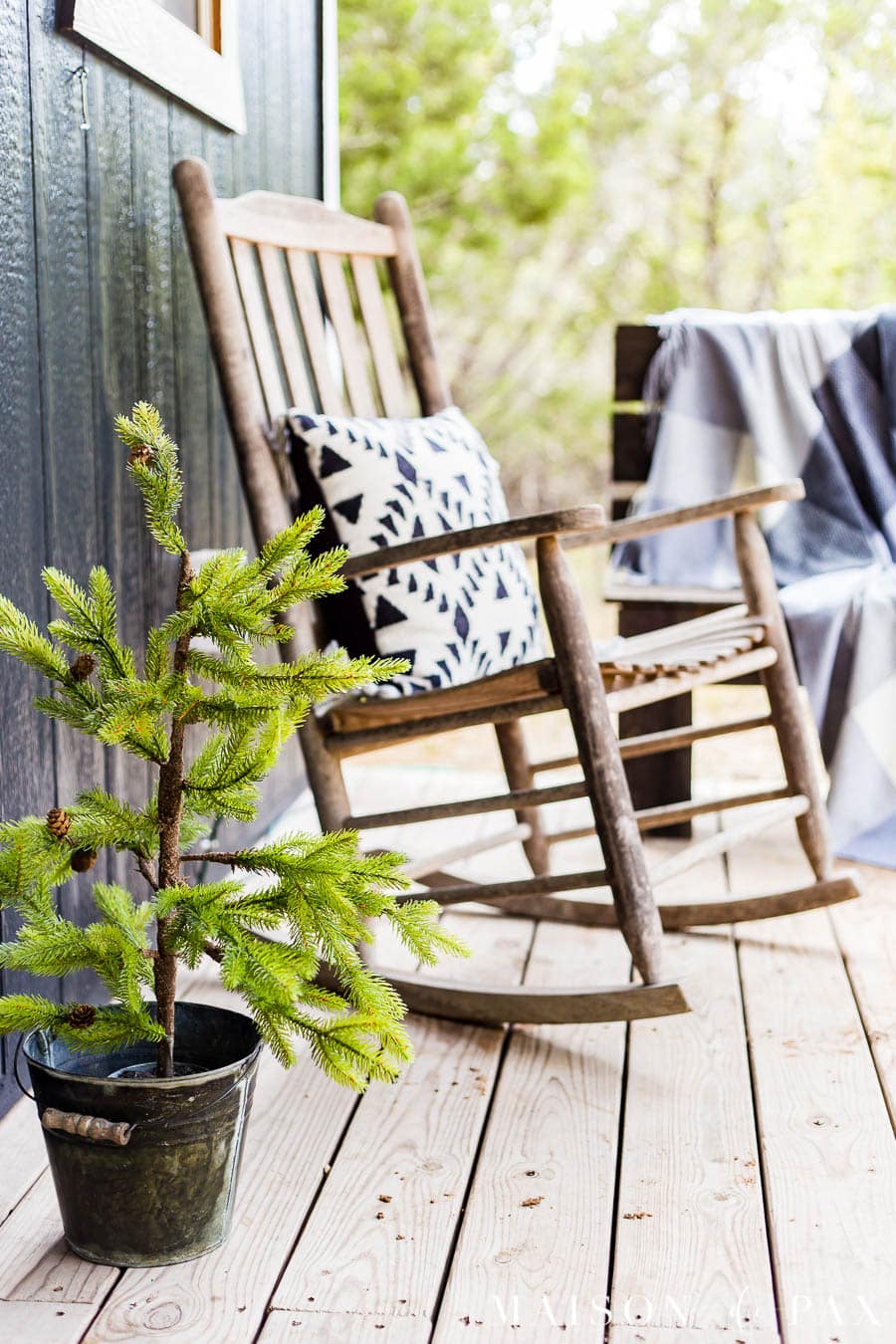 tiny christmas tree beside a rocking chair on a farmhouse porch