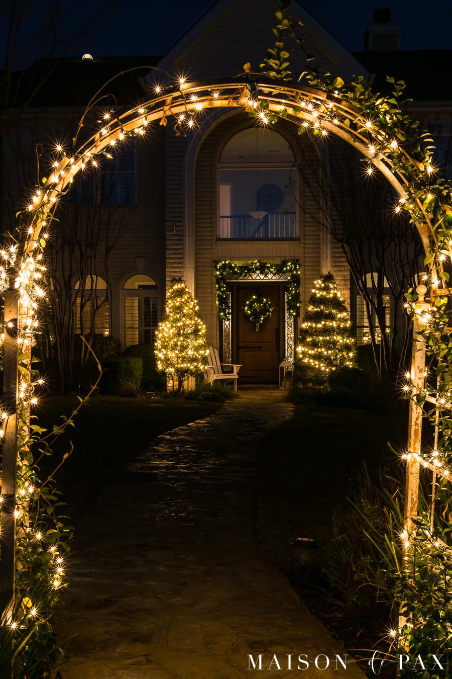 lit archway in front yard of house lit up with Christmas lights | Maison de Pax