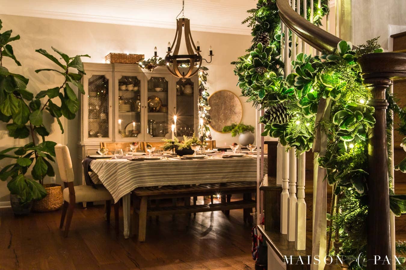 stair garland and dining room all lit up for Christmas