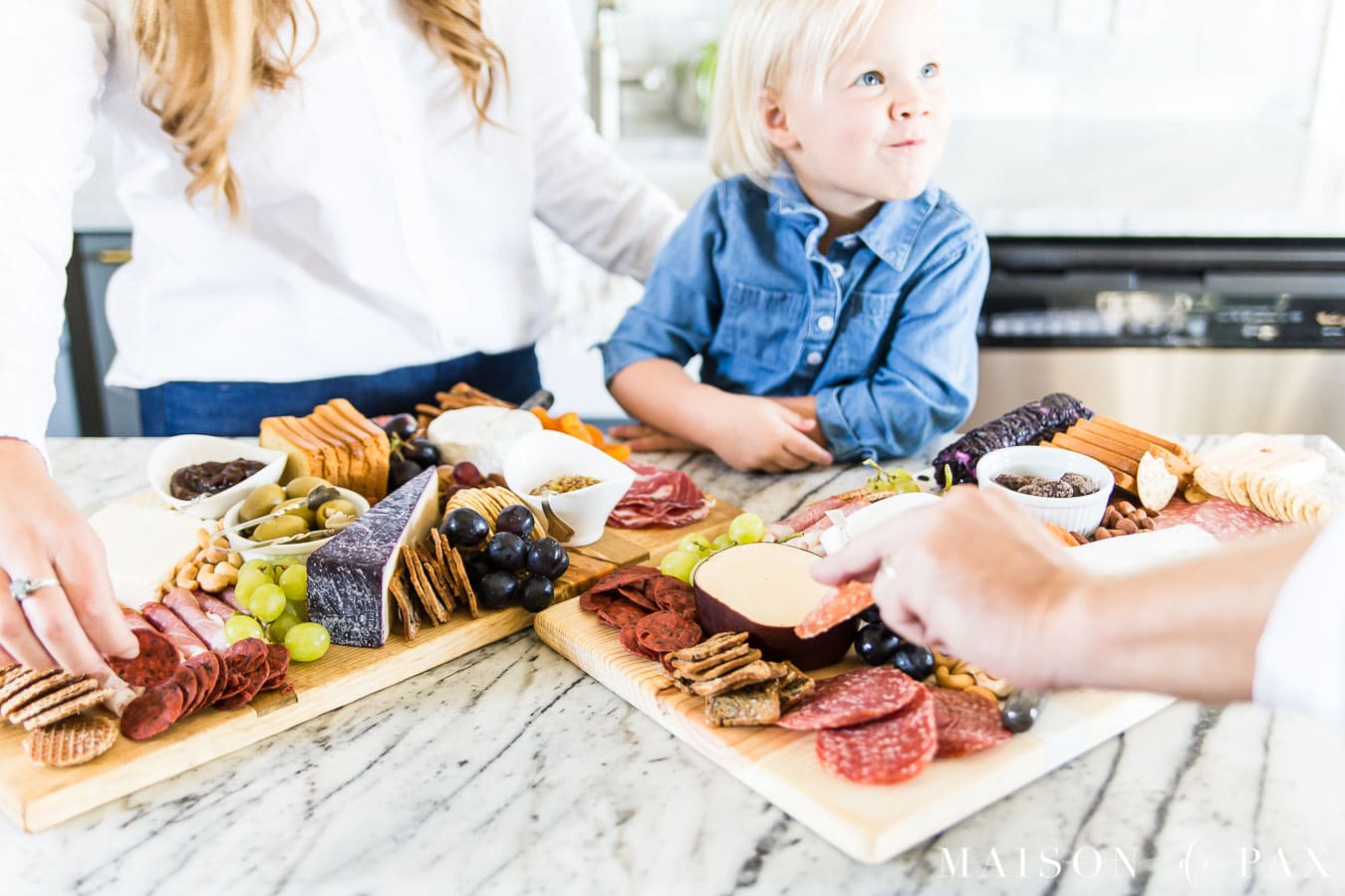 family gathered around charcuterie board in kitchen | Maison de Pax