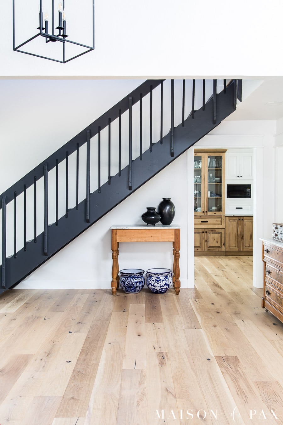 light wood floors, white walls, black stairs with black iron balusters