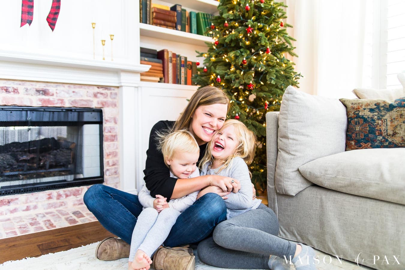 woman and daughters laughing in front of Christmas tree with white twinkle lights | Maison de Pax