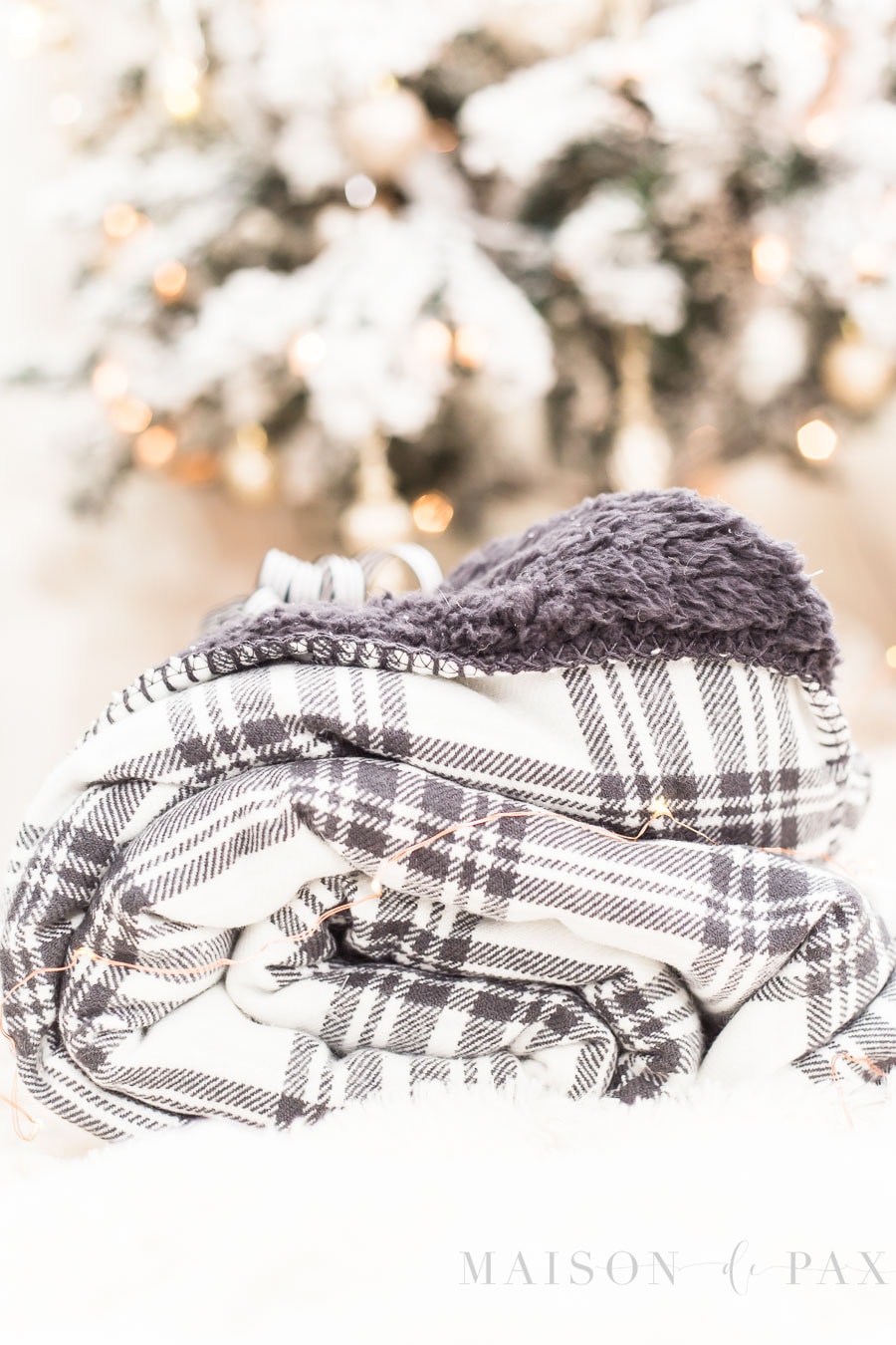 black and white plaid fleece blanket in front of twinkling Christmas tree lights
