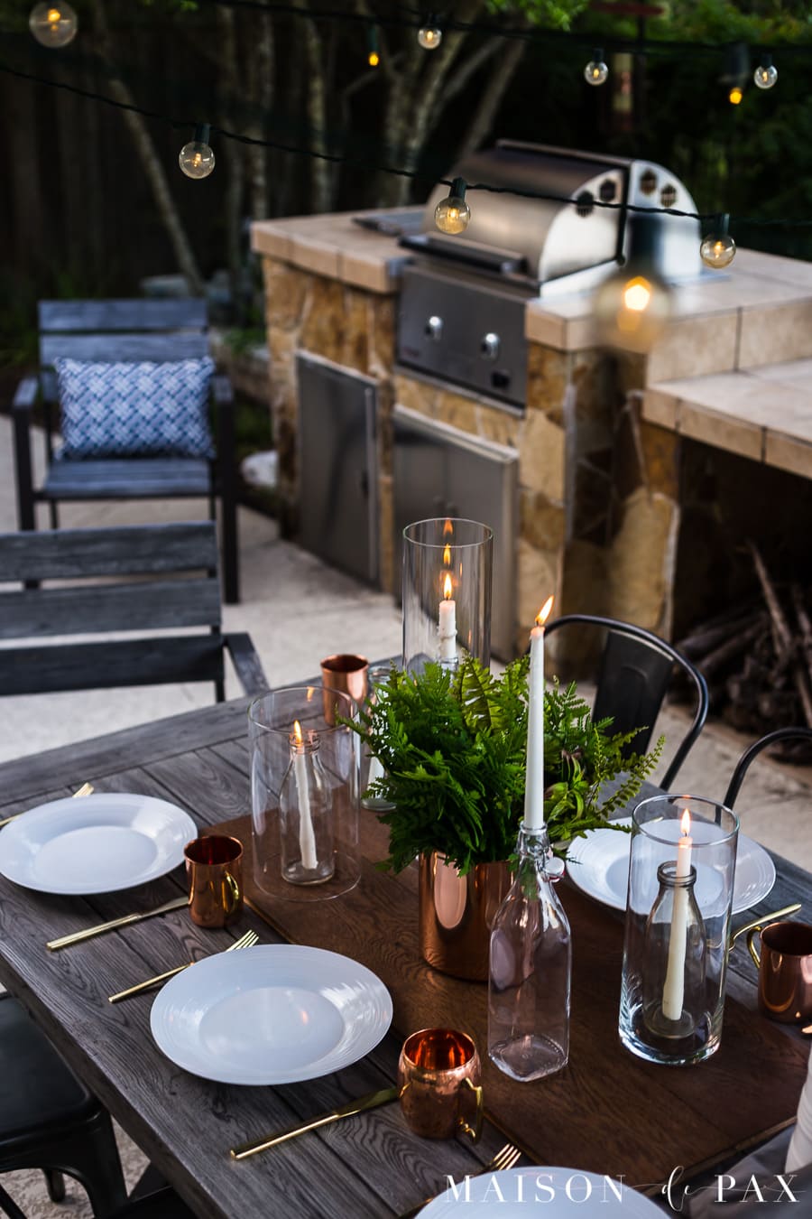 String lights and candles make this outdoor dining magical. Get more tips for outdoor summer dining! #outdoordining #outdoorentertaining #summerentertaining #stringlights