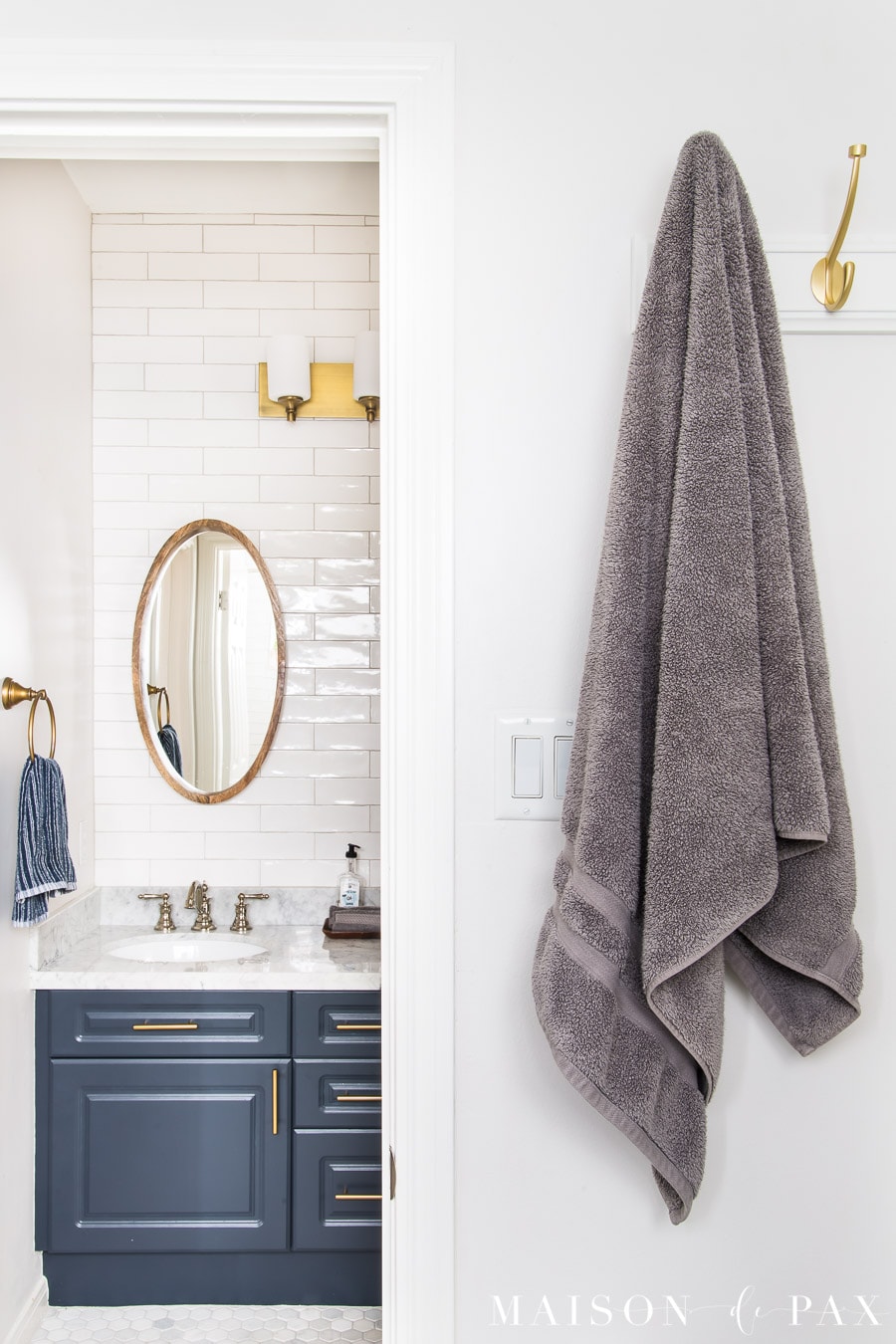 gray towel hanging from gold hooks with a navy vanity beyond