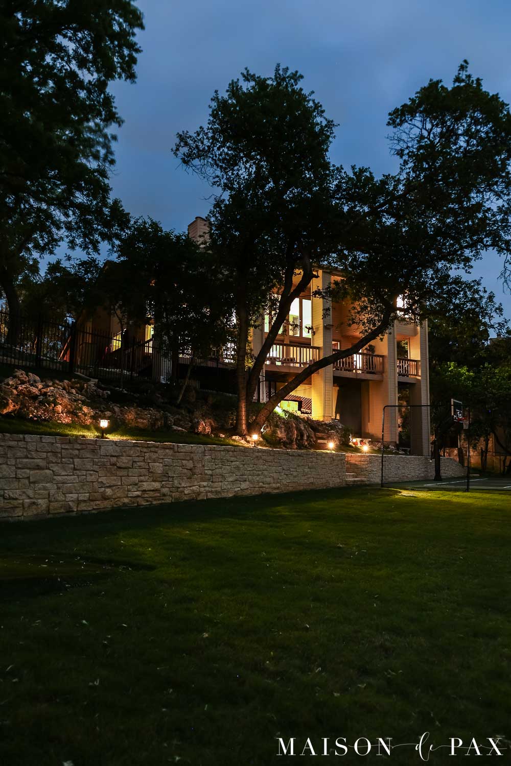 backyard with stone retaining wall, lit up at night