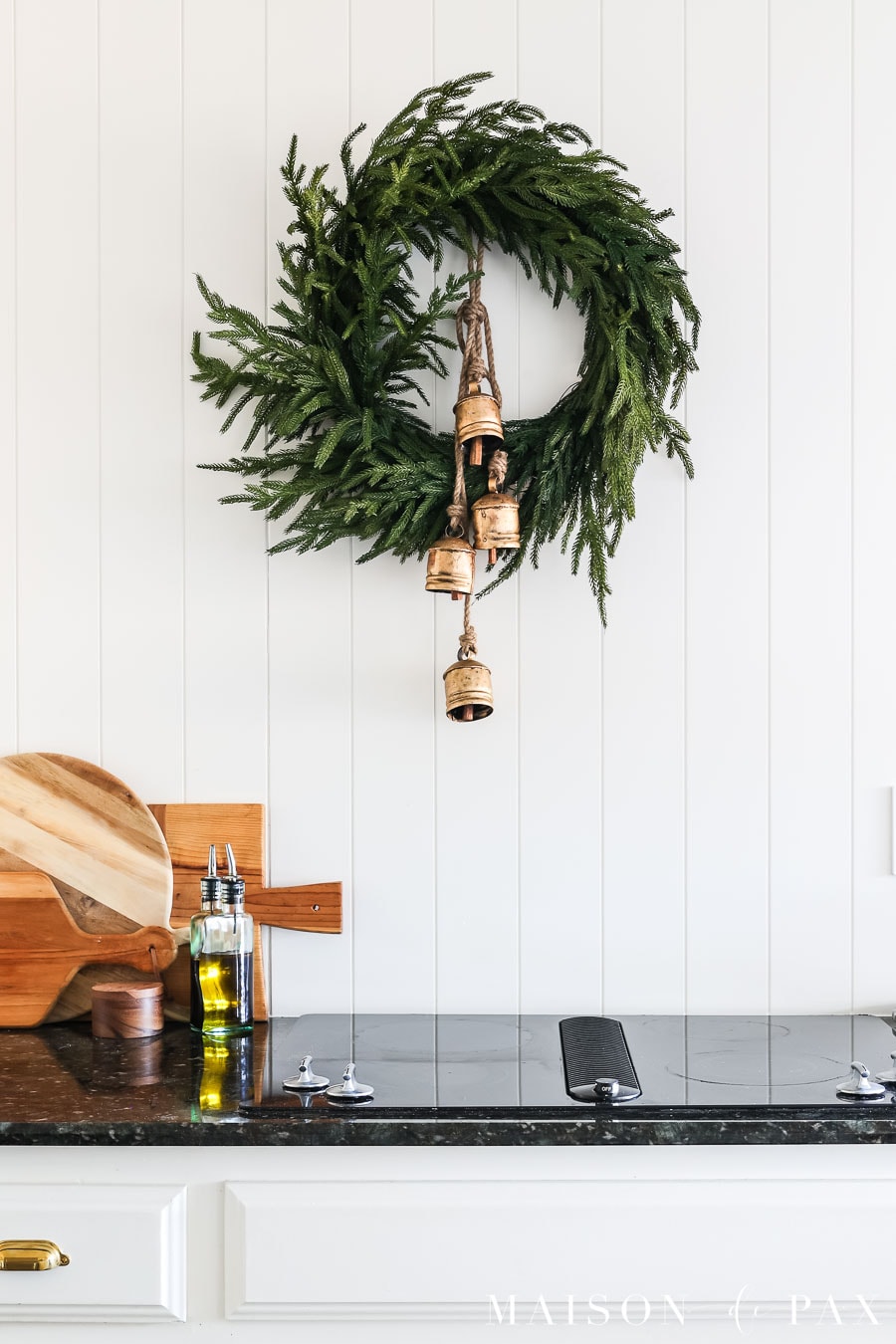 simple pine wreath with gold bells hanging on painted wall with command hook
