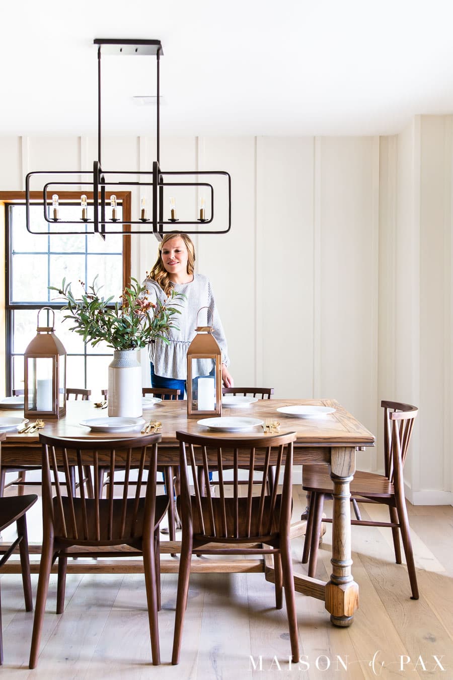 woman arranging stems at a large wood dining table | Maison de Pax