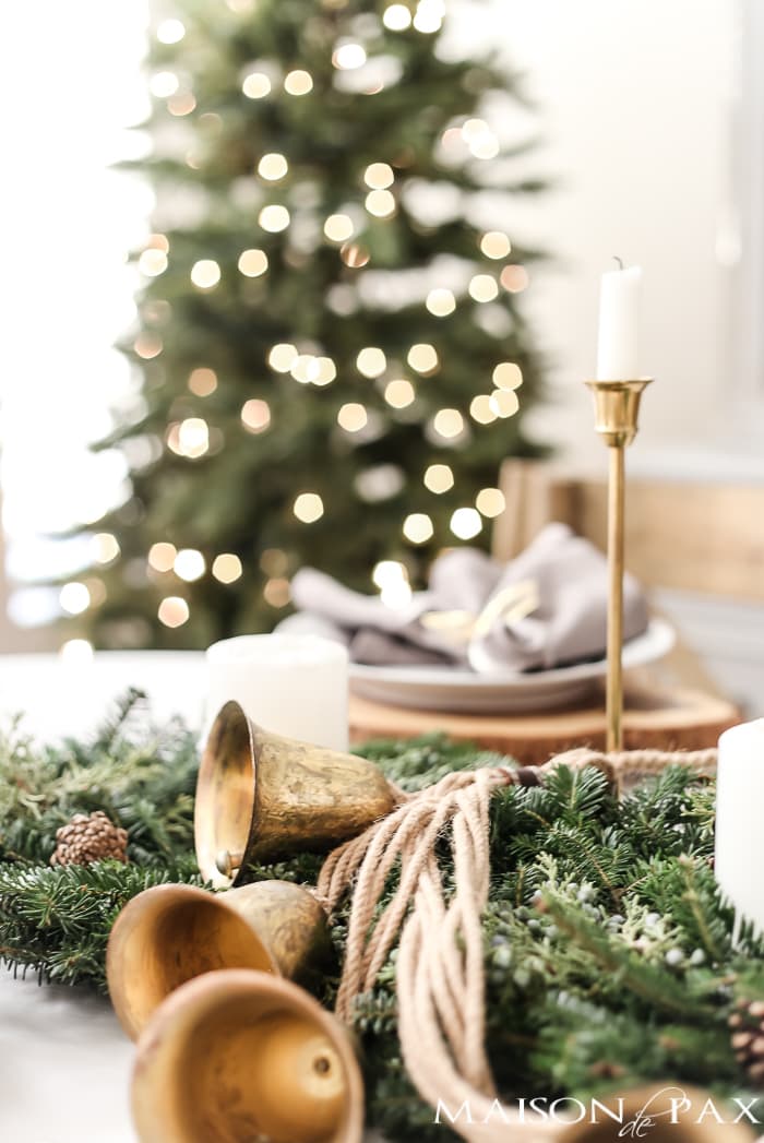 gold sleigh bells and green wreaths and brass candlesticks for a holiday centerpiece - Maison de Pax