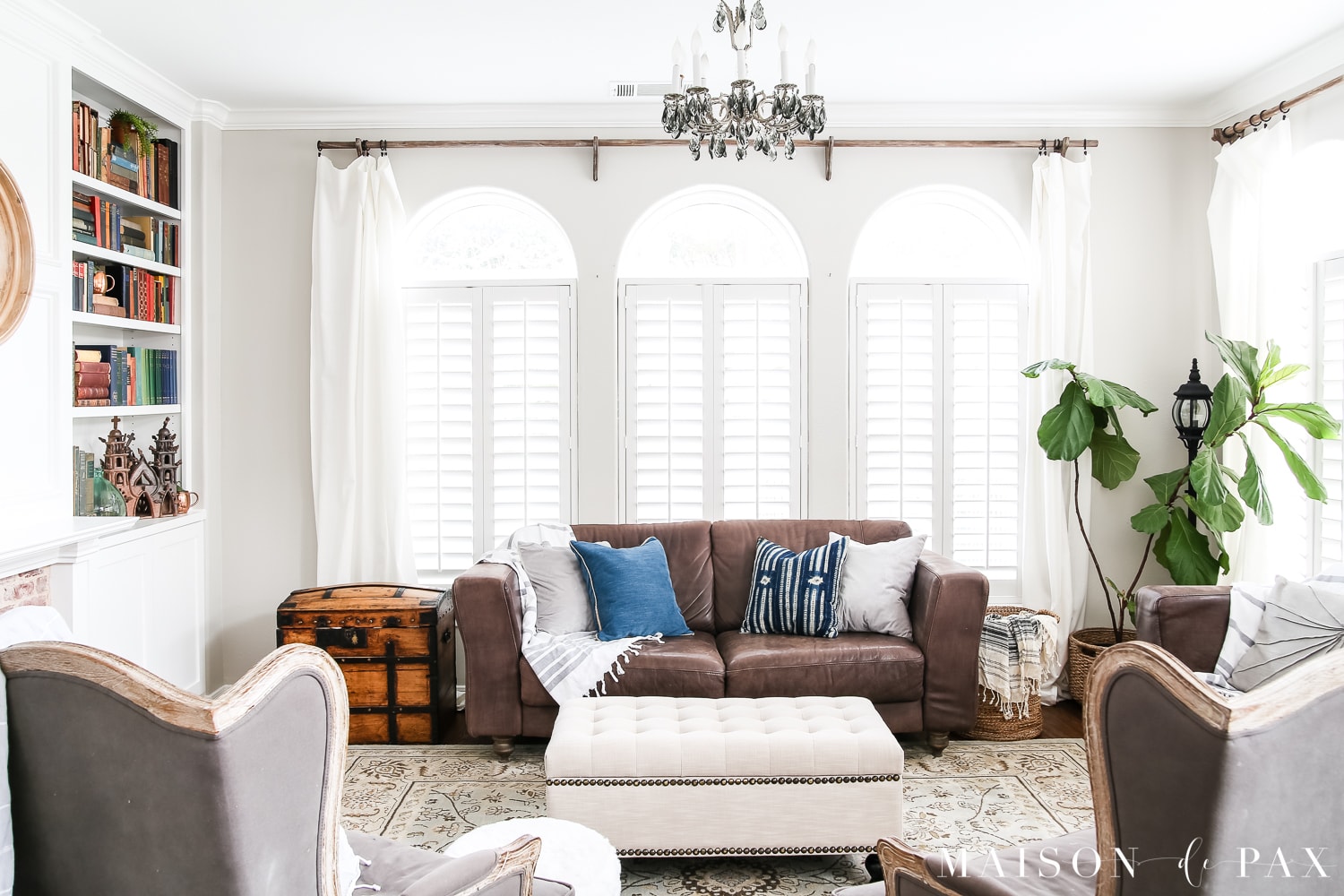 Lighten up leather couches with turkish towel throws and cute pillows. Wondering how to seasonally decorate your living spaces without going to too much trouble?  Get my best tips for transitioning from winter whites to neutrals, blues, and greens for a spring living room. #springdecor #springdecorating #springlivingroom #antiquebooks #howtodecorate #seasonaldecor #seasonaldecorating