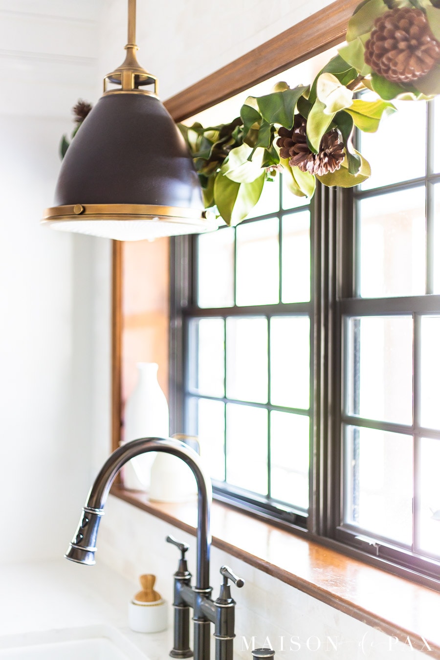 magnolia leaf garland and pendant light over farm sink | Maison de Pax