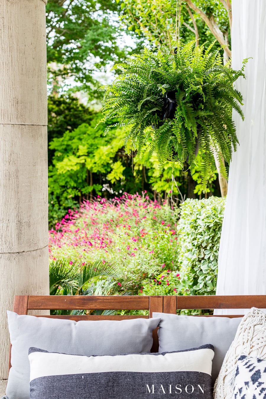 Gorgeous black and white patio with hanging plants... Learn how to make a wine bottle plant waterer to keep your hanging plants hydrated! #winebottlewaterer #winebottle #upcycle #garden #gardening #diygardening #hangingplants #bostonfern #summergarden